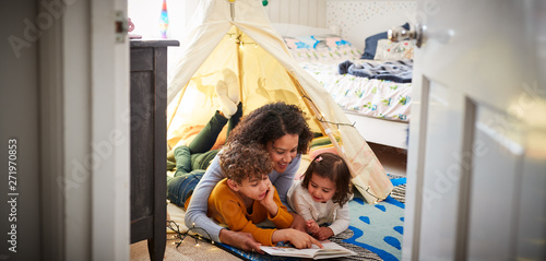 Obraz na płótnie Single Mother Reading With Son And Daughter In Den In Bedroom At Home