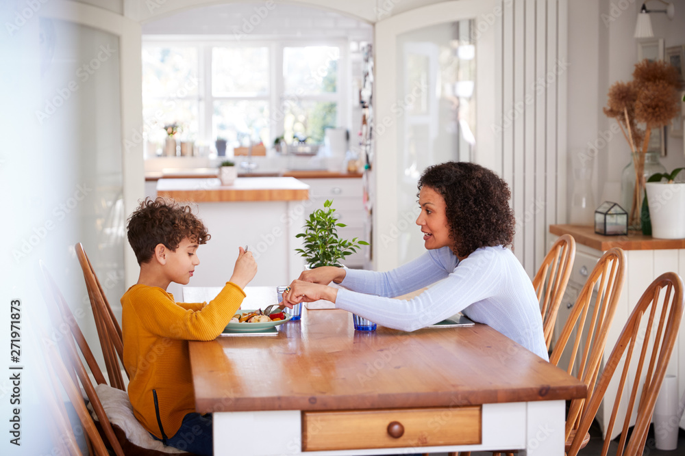 Single Mother Sitting At Table Eating Meal With Son In Kitchen At Home Single Mother Sitting At Table Eating Meal With Son In Kitchen At Home