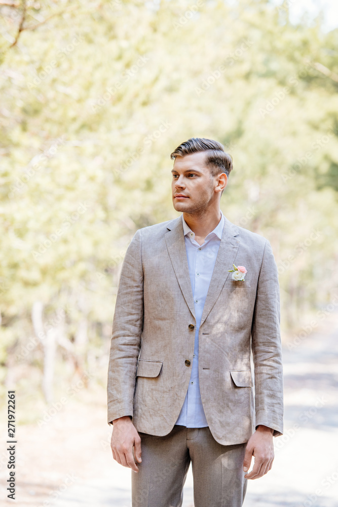 pensive bridegroom in formal wear with boutonniere looking away pensive bridegroom in formal wear with boutonniere looking away