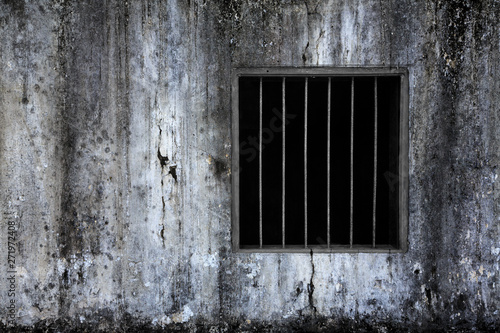 Window with rusty bars on old grungy prison cell wall