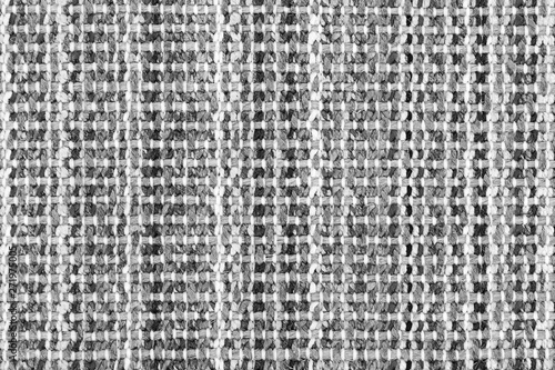 White and black knitted fabric background texture. gray fabric with a pattern. Fragment grey wool carpet, bright wicker dark rug