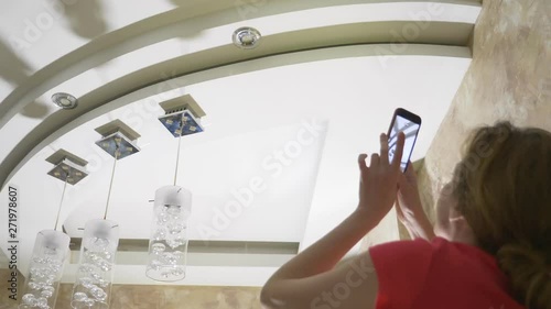 Water damage. concept of flooding the apartment and property insurance. a woman takes a photo on the phone as water drips from the ceiling of her apartment