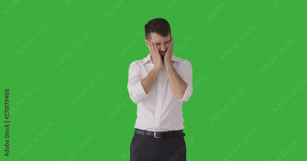 Sleepy businessman trying to wake himself up slapping on his cheek over green background Sleepy businessman trying to wake himself up slapping on his cheek over green background