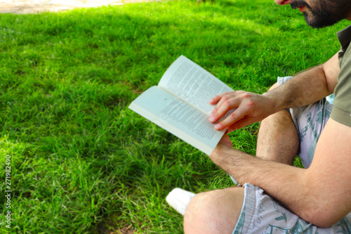 The young man reads book on the grass field