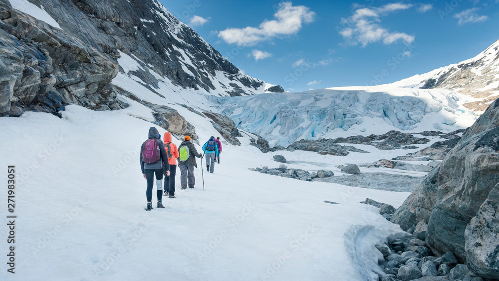 a group of people tourists are coming at the foot of  glacier Fabergstolsbreen in the mountains of Norway