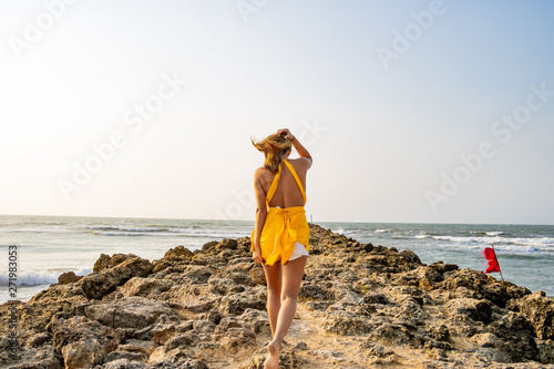  young beautiful woman walks towards the sea and touches her head