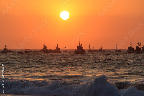 sunset over mancora beach with fisher boats, peru