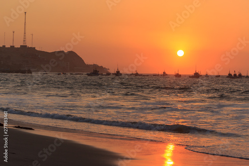 sunset over mancora beach with fisher boats, peru