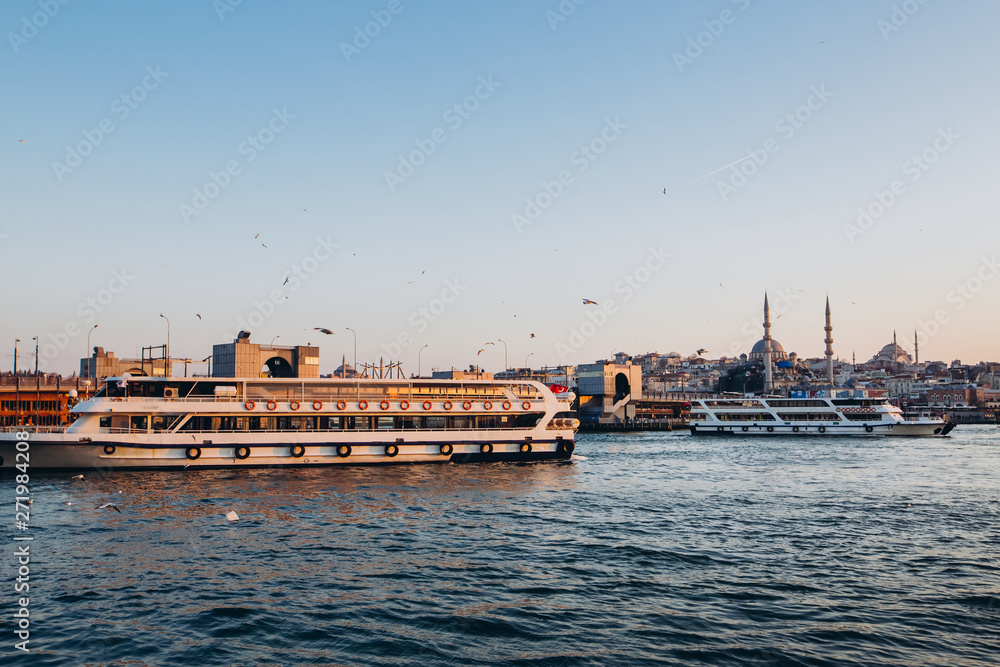 Scenic view of Istanbul and the Galata Tower from the Bosphorus Bay, shot on a sunny day. Vintage fishing boats on the coast in Istanbul. Passenger ferry through the Bosphorus