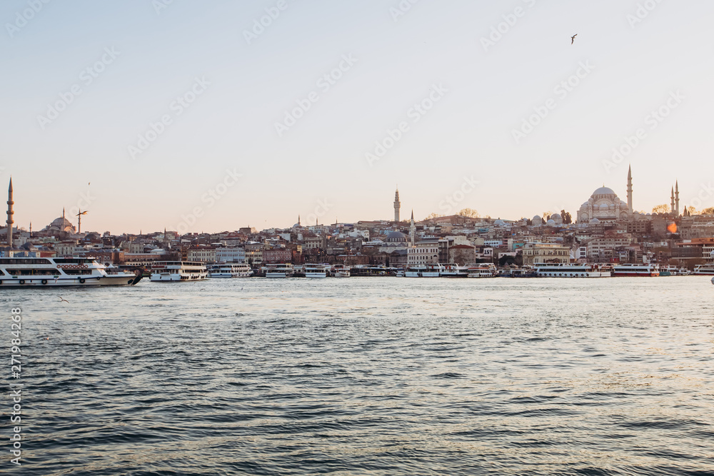 Scenic view of Istanbul and the Galata Tower from the Bosphorus Bay, shot on a sunny day. Vintage fishing boats on the coast in Istanbul. Passenger ferry through the Bosphorus