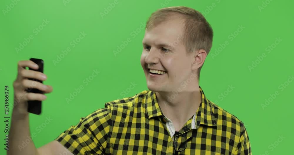Caucasian young man in yellow shirt taking nice selfies on the smartphone Caucasian young man in yellow shirt taking nice selfies on the smartphone