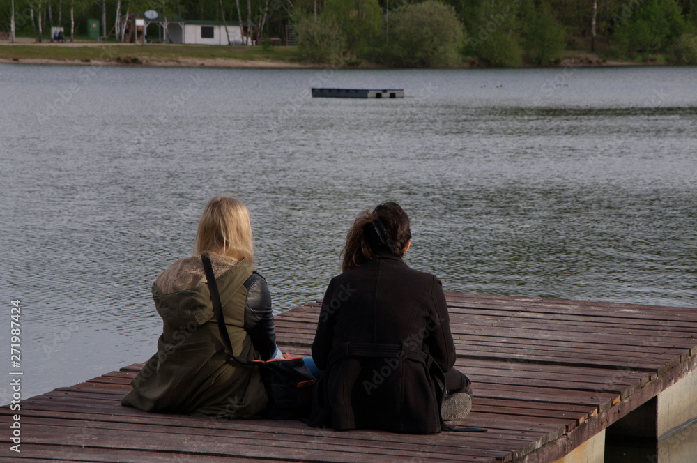 Two girls have a rest sitting by the lake.