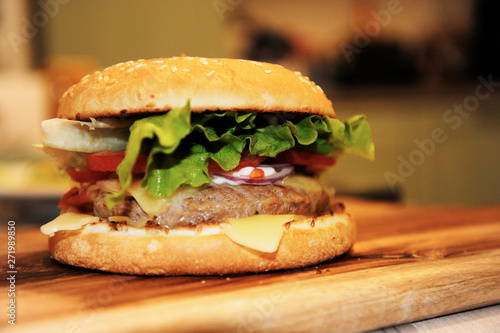 Closeup of home made beef burger with lettuce and mayonnaise served on little wooden cutting board.