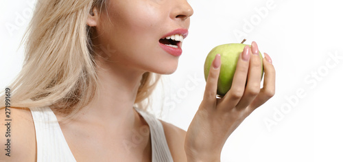 Beautiful blonde woman with healthy white teeth holding green apple isolated on white background