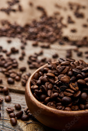 close up view of fresh roasted coffee beans in bowl on wooden board