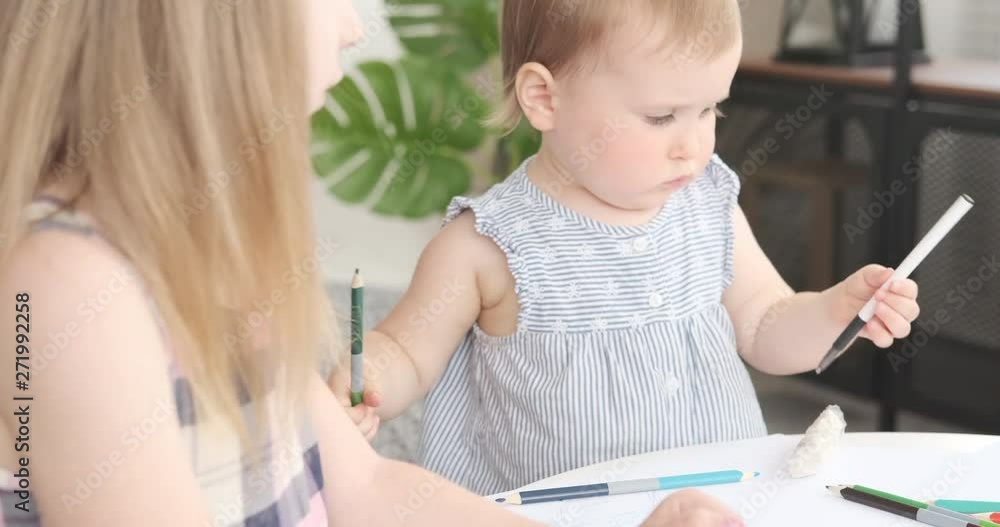 Girl with baby sister learning to draw using colored pencil and pen Girl with baby sister learning to draw using colored pencil and pen