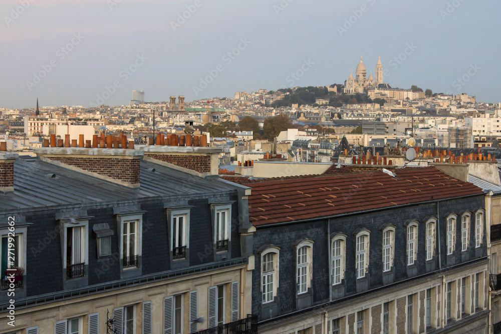 Amazing picturesque view of rooftops of Paris and beautiful facades of residential buildings on the streets of France. View of the large hill Montmartre and Basilica of the Sacred Heart of Paris above