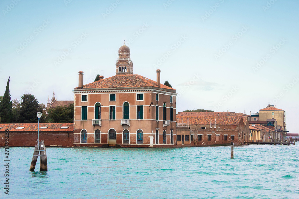 Venetian lagoon and bay in the Adriatic Sea. Old architecture, red tile roof and dome. Blue water and sky. Tourism and leisure in Italy. traditional Italian architecture, a city on the water.