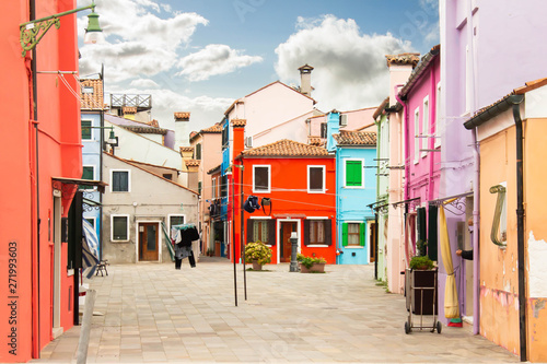 Bright street with colorful multi colored painted buildings. Sunny day and stylish facades of redifential buildings. Traditional architecture. Tiled brown roof and shutter windows. Drying linen, rope. © Daniil
