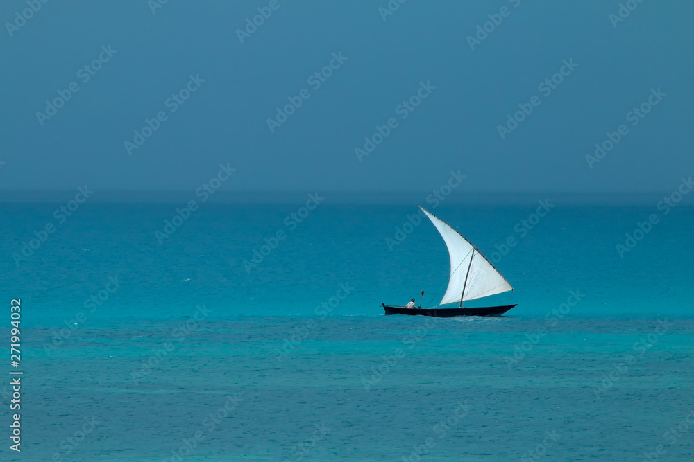 Wooden sailboat (dhow) on water with cloudy sky, Zanzibar island.