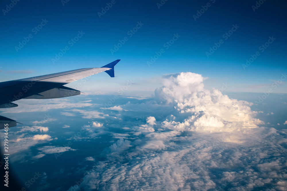 Fototapeta premium wing of the plane against the blue sky with clouds. view from eluminator to the wing of the aircraft against the sky. Concept: flight, vacation, tourism.