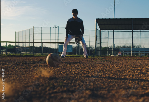 Photography Player fielding grounder on baseball field during dusk.