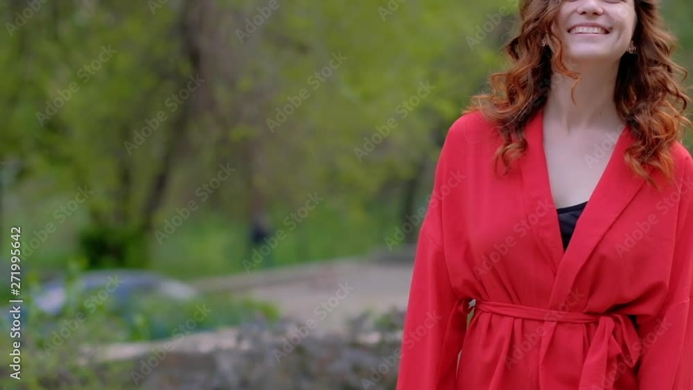 Confident smiling woman walking outside. Red outfit and curly ginger hair Confident smiling woman walking outside. Red outfit and curly ginger hair