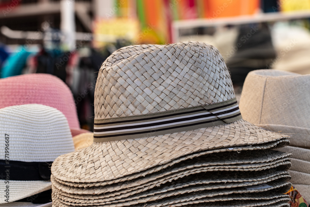 Straw hats background. Closeup with selective focus on a stack straw hats for sale with blurred market shop background. Macro.