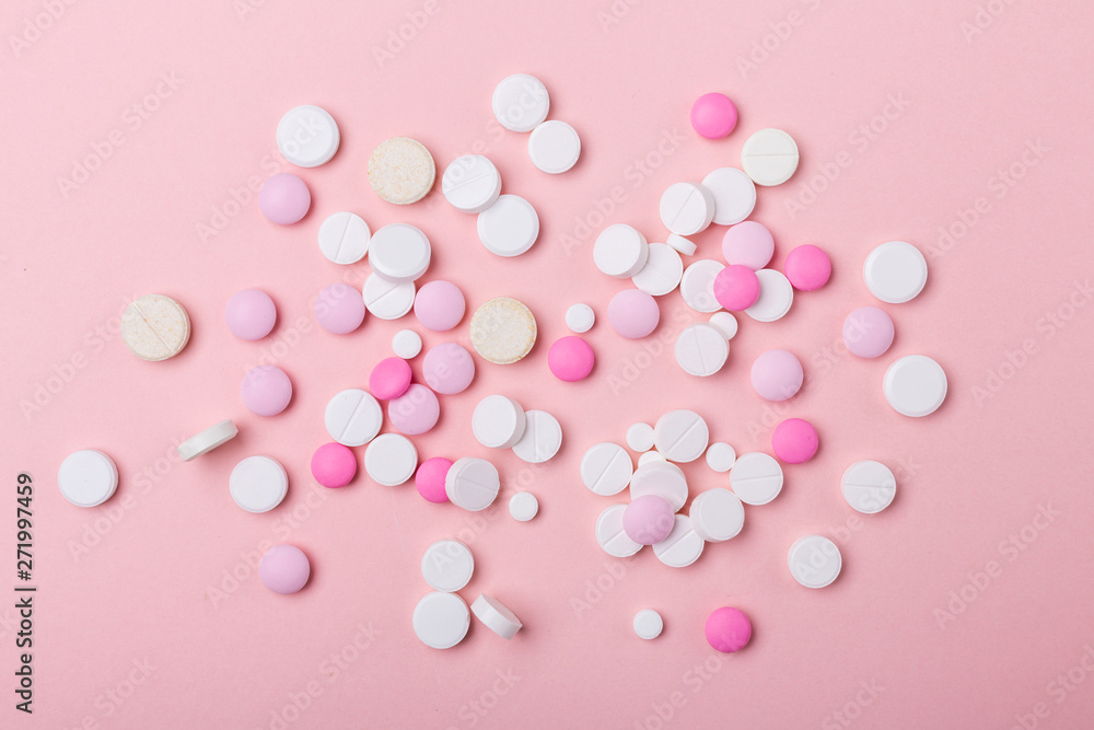 Pink and white pills on pink background. Heap of assorted various medicine tablets and pills. Health care.