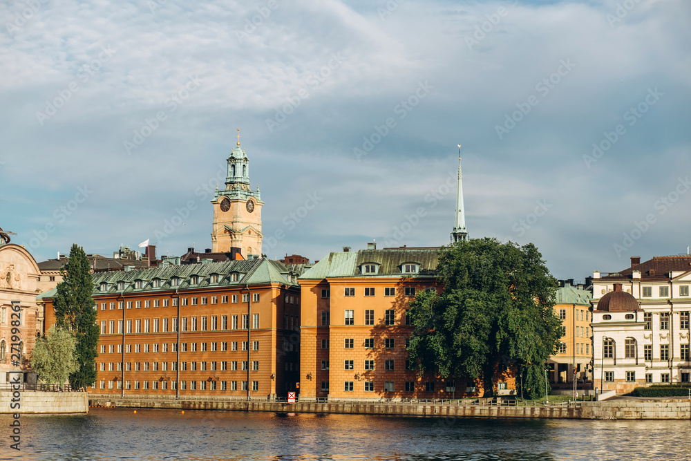 Scenic summer panorama of the Old Town (Gamla Stan) architecture in Stockholm, Sweden. view from Monteliusvagen hill on island Riddarholm and tower of church. Lake Malaren with blue sky, white clouds.