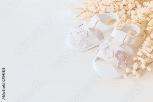 children's sandals and a bouquet of flowers close-up. delicate background with baby shoes and flowers.