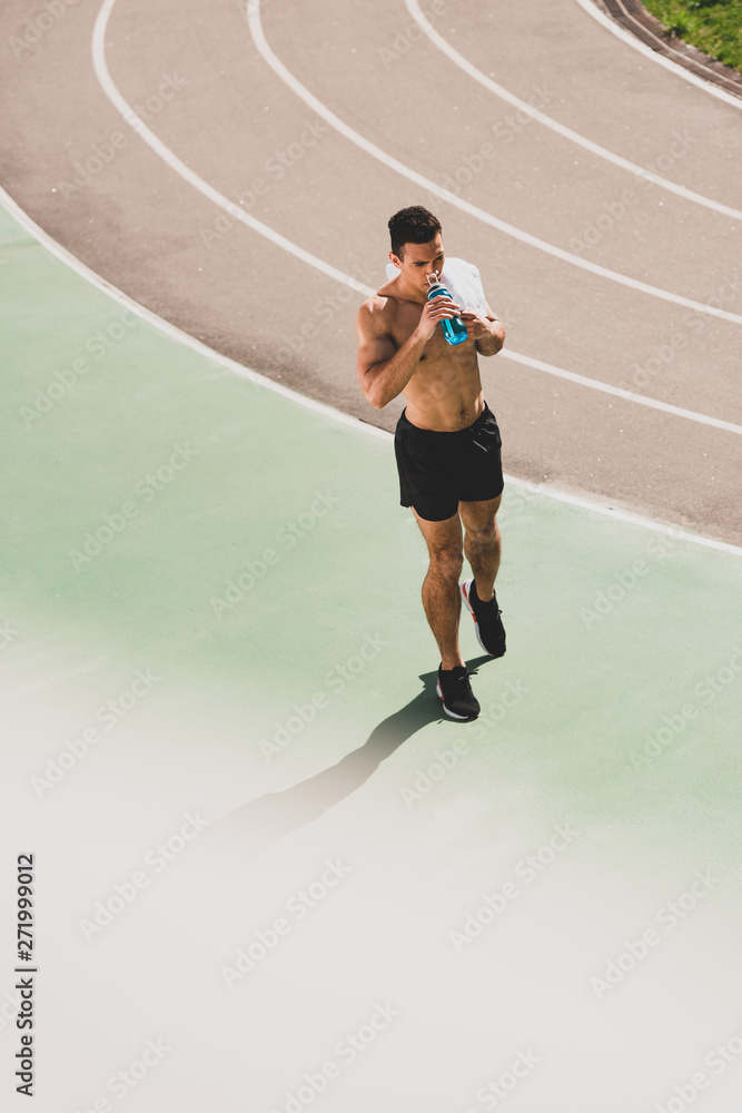 Obraz premium mixed race sportsman holding towel and sport bottle at stadium
