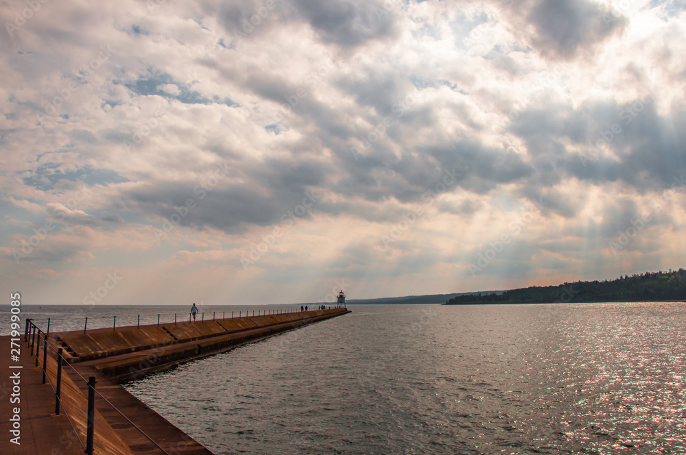 Two Harbors Breakwall and navigation light in Agate Bay of Lake Superior with dramatic light through the clouds