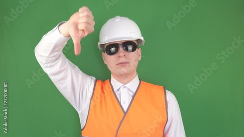 The head specialist in black glasses at the construction site shows the gestures of the team to the crane operator in the crane, green background, hromakey, safety engineering, slinger photo