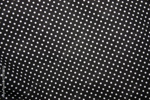 Black fabric and white tiny polka dot background, close-up.
