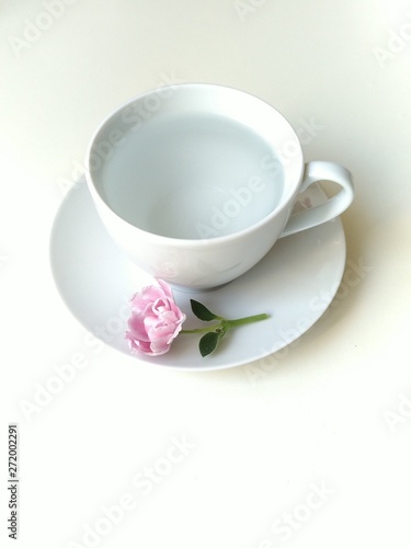 a small bouquet of light pink flower at the foot of a tea coffee Cup