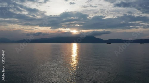 Beautiful Vietnamese landscape of a golden sunset reflecting over the ocean with mountains and traditional fishing boat. photo