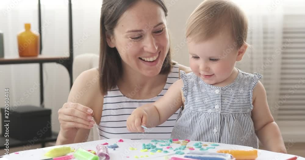 Mother and baby daughter dancing while playing with plasticine at home Mother and baby daughter dancing while playing with plasticine at home