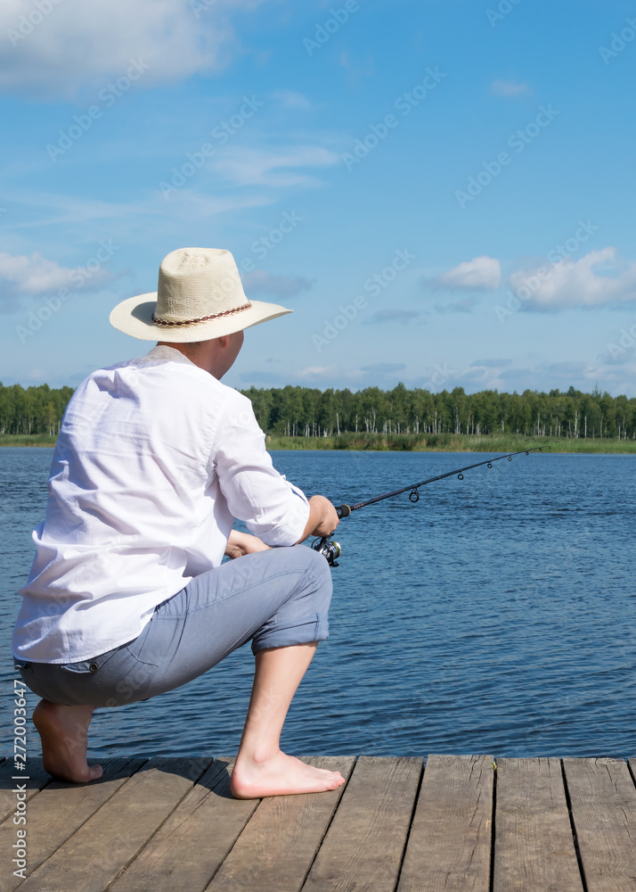 a fisherman is sitting on a pier with a fishing rod waiting for a big fish to bite a fisherman is sitting on a pier with a fishing rod waiting for a big fish to bite