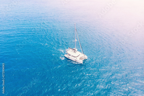 Pleasure white yacht with sail stands on coral reef in blue transparent turquoise water. Concept travel. Aerial top view.