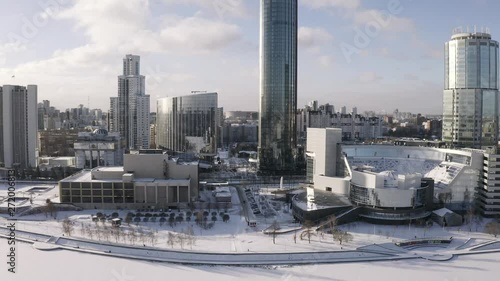 Aerial view of beautiful quay covered with snow and of modern glass buildings in the city center in winter sunny day. Action. Urban landscape, Ekaterinburg, Urals, Russia photo