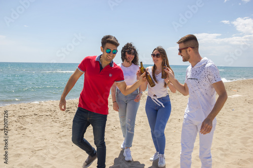 Group of friends celebrating Summer on the beach toasting with beer