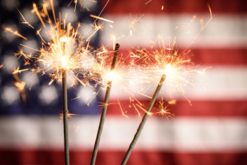 Sparklers Closeup With American Flag In Background. Celebrating 4th Of July Independence Day