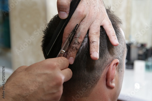 Close-up of a male master barber cutting hair with a scissors and comb. Concept for hairdressers.