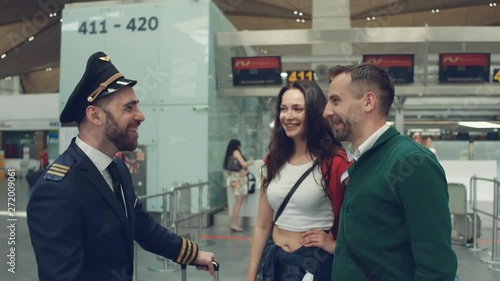 Happy couple talking to the handsome pilot standing in the airport terminal. photo