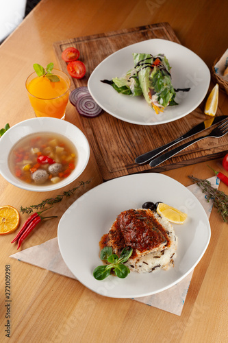 Set lunch menu in a restaurant: fish with steamed rice, light vegetable soup with meatballs and vegetarian spring roll