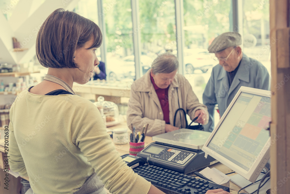 Elderly couple at cashier desk paying to teller in local zero waste store. Elderly couple at cashier desk paying to teller in local zero waste store.