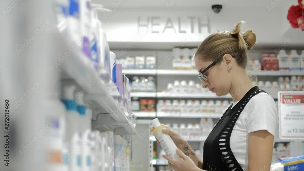 Young girl looking at medicine. Attractive woman looking, choosing and buying health, care, beauty products in pharmacy. Health care and pharmacology concept Young girl looking at medicine. Attractive woman looking, choosing and buying health, care, beauty products in pharmacy. Health care and pharmacology concept