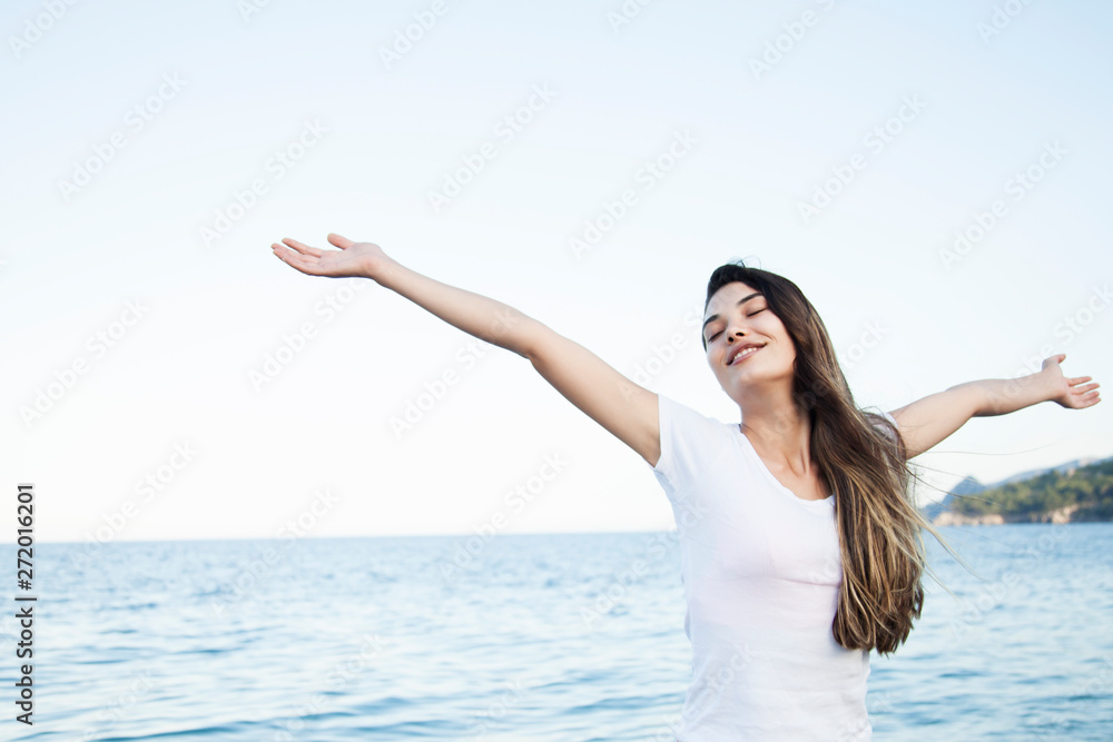Happy woman standing arms outstretched with enjoy life on the beach at sea Happy woman standing arms outstretched with enjoy life on the beach at sea