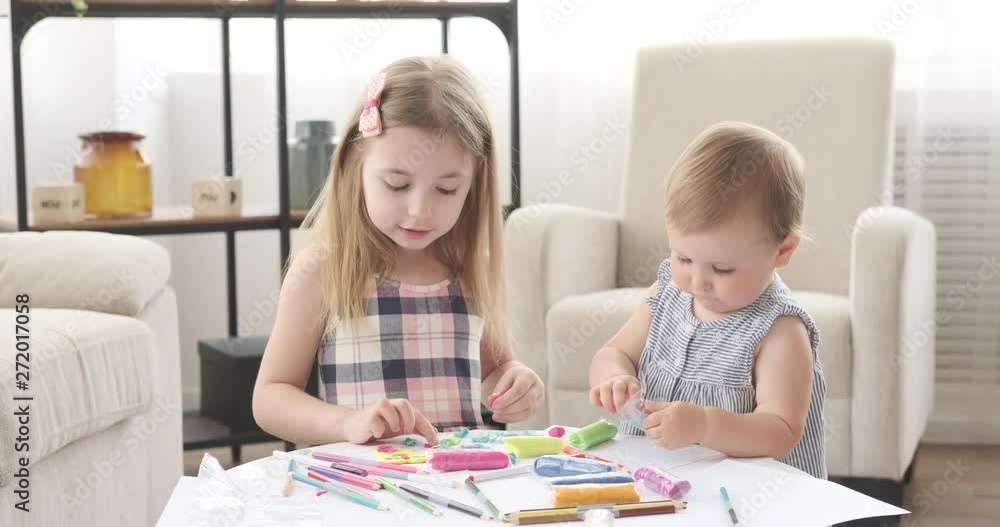 Baby girl with her sister enjoying playing with plasticine at home Baby girl with her sister enjoying playing with plasticine at home